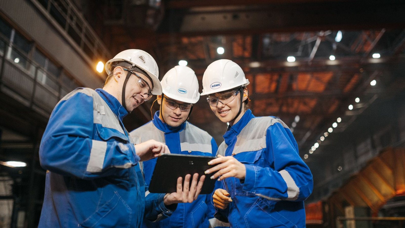 Operations and engineering professionals reviewing production data on a tablet inside a manufacturing facility.